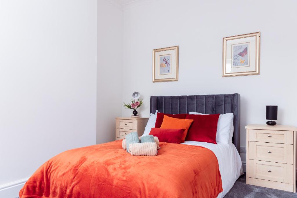 a bedroom with a bed with orange sheets and red pillows at Brown Ball in Barrow in Furness