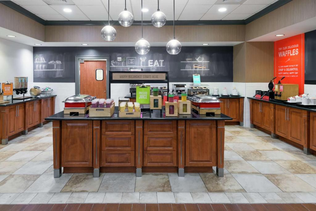 a large kitchen with a counter with food on it at Hampton Inn & Suites Orlando Airport at Gateway Village in Orlando