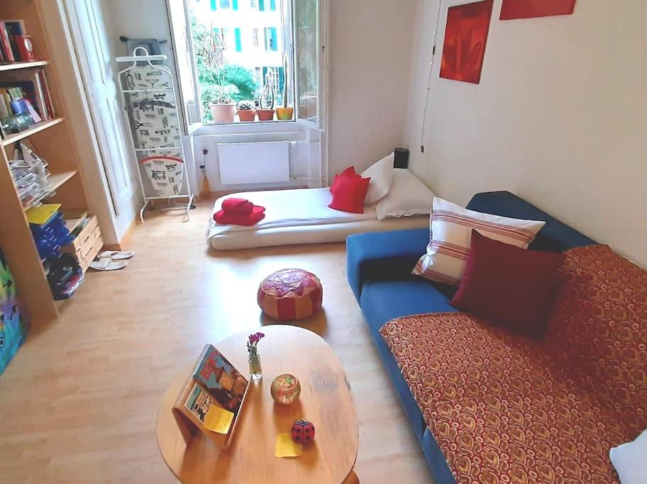 Bern room near Main Station في برن: غرفة معيشة مع أريكة زرقاء وطاولة