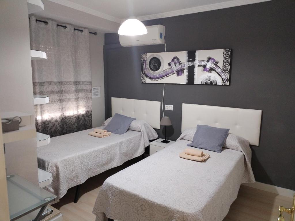 Cette chambre comprend 2 lits et une photo murale. dans l'établissement Apartamento con PARKING PRIVADO GRATIS INCLUIDO, à Cordoue