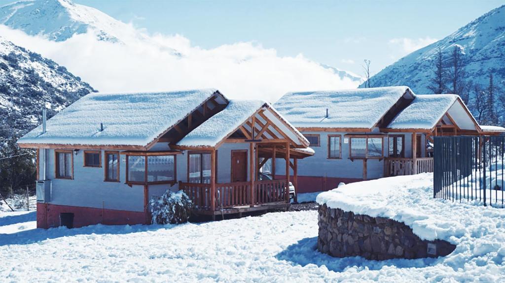 una casa cubierta de nieve con montañas en el fondo en Posada del Jinete, en San José de Maipo