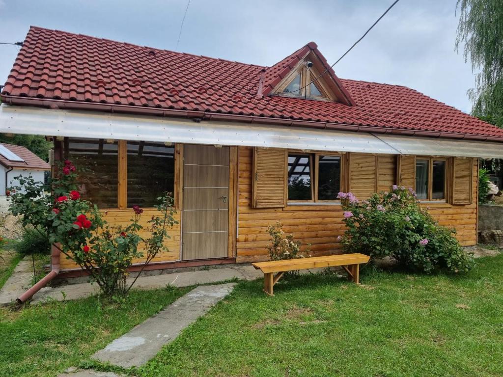 ein Holzhaus mit einer Bank davor in der Unterkunft Cabana rustica de vacanta in Braşov