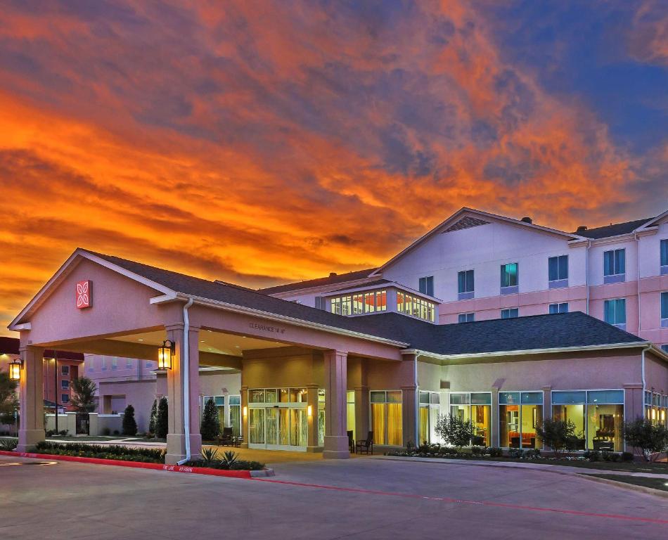 a hotel building with a sunset in the background at Hilton Garden Inn Midland in Midland