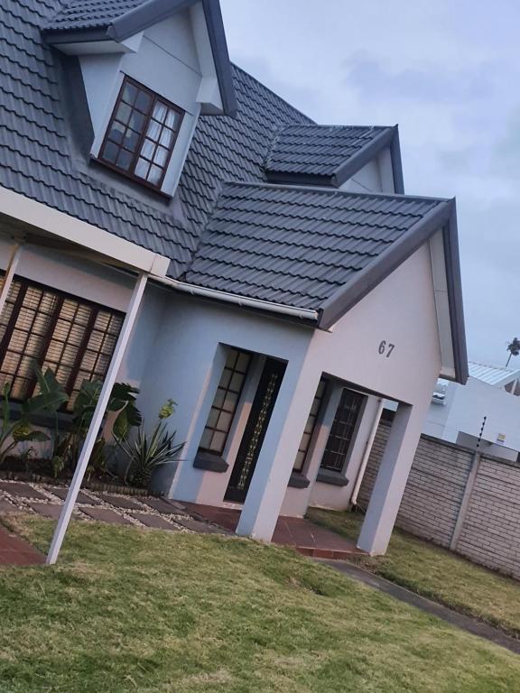 a white house with a black roof at 67@18th Avenue Beach View, in East London