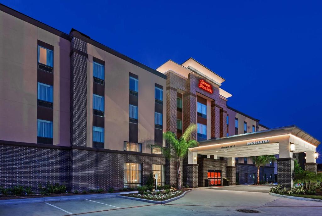 a hotel building with a palm tree in front of it at Hampton Inn & Suites Houston I-10 West Park Row, Tx in Katy