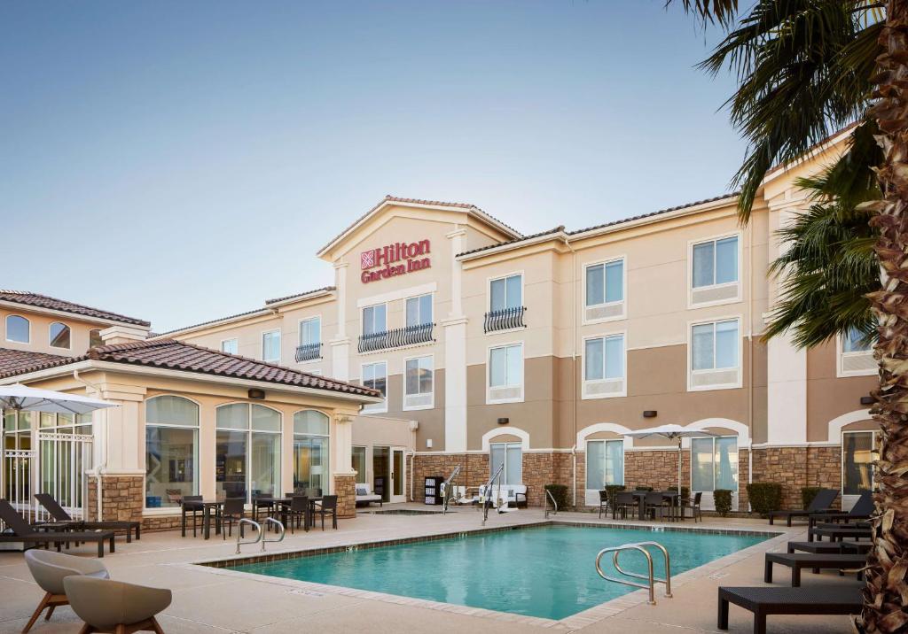 a hotel with a pool and tables and chairs at Hilton Garden Inn Las Vegas/Henderson in Las Vegas