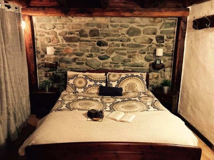 a bed in a room with a stone wall at Appartamento "Verdjats" in Challand Saint Anselme