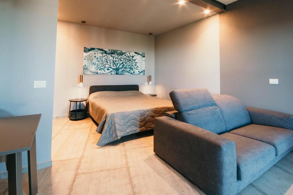 um quarto com uma cama e um sofá em Appartamento Meda - Lakeside Leisure & Business em Cissano