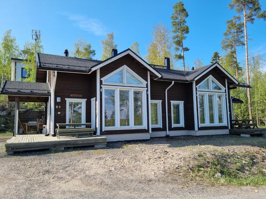 ein braunes Haus mit einer Veranda und Fenstern in der Unterkunft Villa Tumppu in Muurame