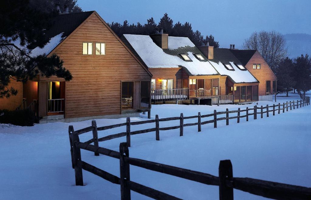 uma casa de madeira na neve com uma cerca em Christmas Mountain Campground em Wisconsin Dells