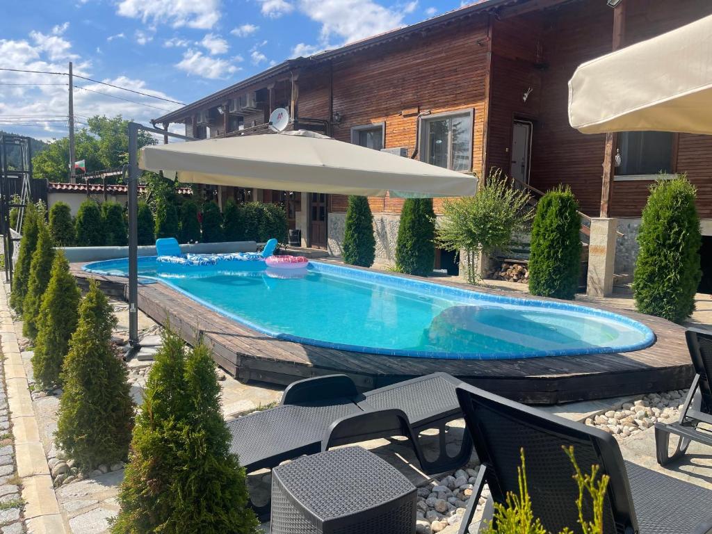 a swimming pool with an umbrella and chairs at Villa Le Cinema in Shiroki Dol