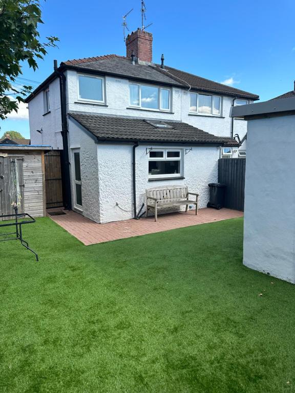 a white house with a bench in a yard at 2 bedroom semi-detached house- sleeps 4 in Newport