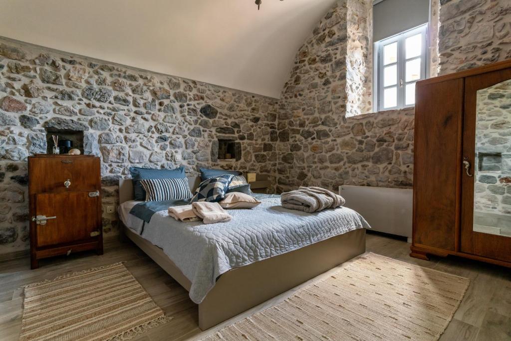 a bedroom with a bed and a brick wall at ENGLEZENA'S GUESTHOUSE in Leonidion