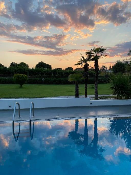 a swimming pool with a palm tree and a sunset at Villa olion in Afitos