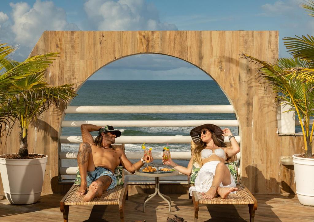 伊列烏斯的住宿－奧帕巴普拉亞酒店，坐在海滩桌子上的男人和女人
