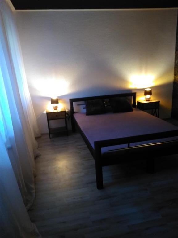 ジーゲンにあるAldo hausのベッドルーム1室(ベッド1台、ランプ2つ、テーブル2台付)