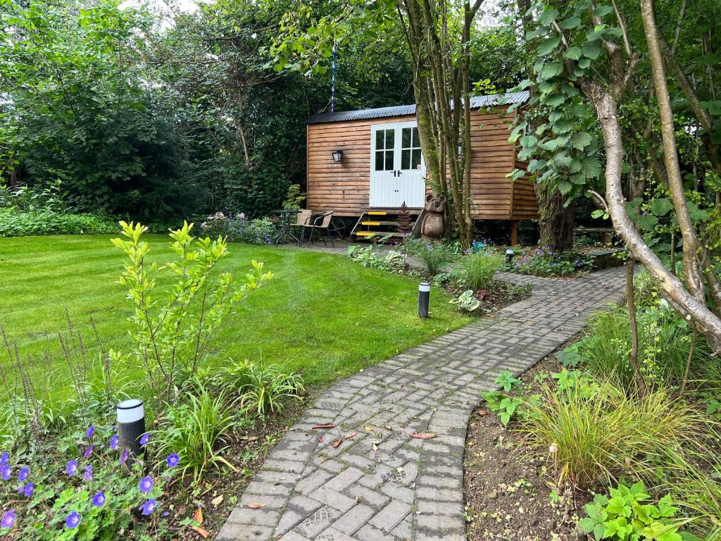 a garden with a cabin and a brick walkway at Tranquil Spot Shepherds Hut in Cinderford