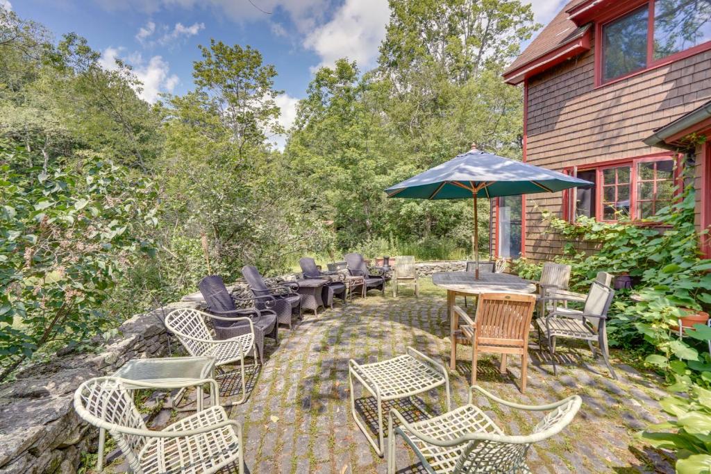 um pátio com mesas e cadeiras e um guarda-sol em Tranquil Washington Home with Sauna, on 70 Acres em Washington