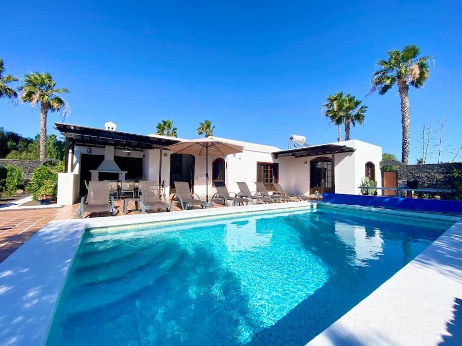 a swimming pool in front of a house with palm trees at VILLA ALICIA by JK Lanzarote in Puerto del Carmen