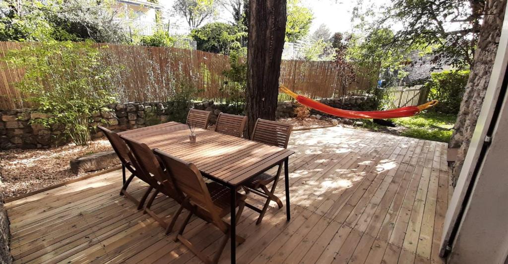 una mesa de madera y sillas en una terraza con hamaca en Maison provençale, jardin arboré et terrasses proche Grignan 8-10pers, en Réauville