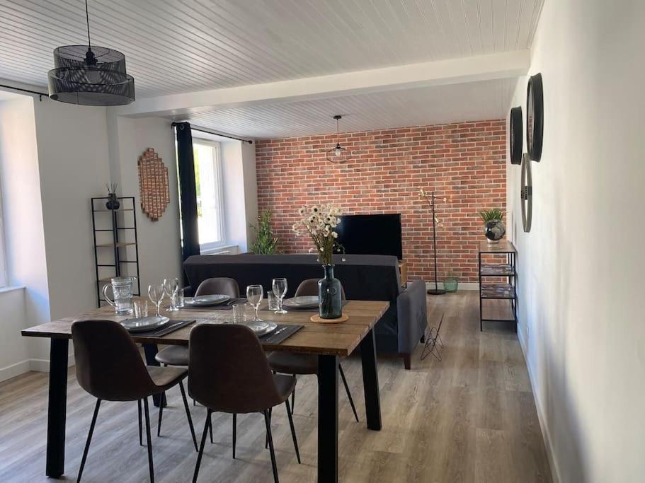 een eetkamer met een tafel en stoelen en een bakstenen muur bij *La Factory / Saint Aignan in Saint-Aignan