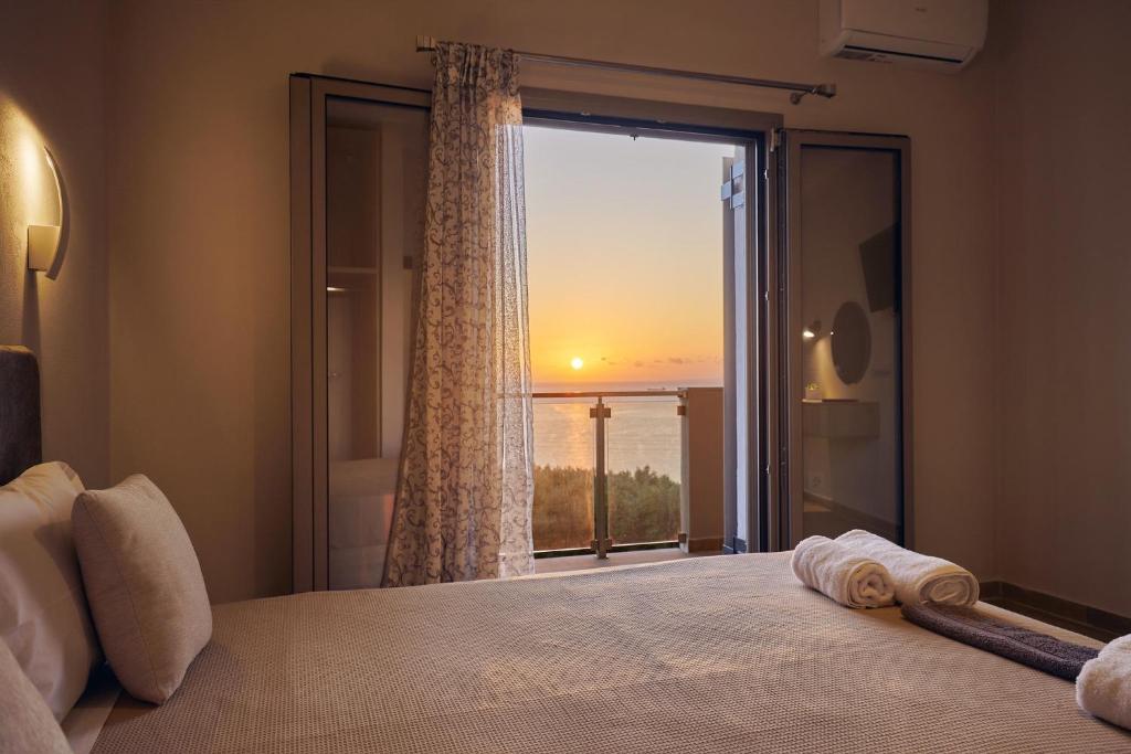 a bedroom with a window with a view of the ocean at Pelagaki Sunrise in Orthoniaí