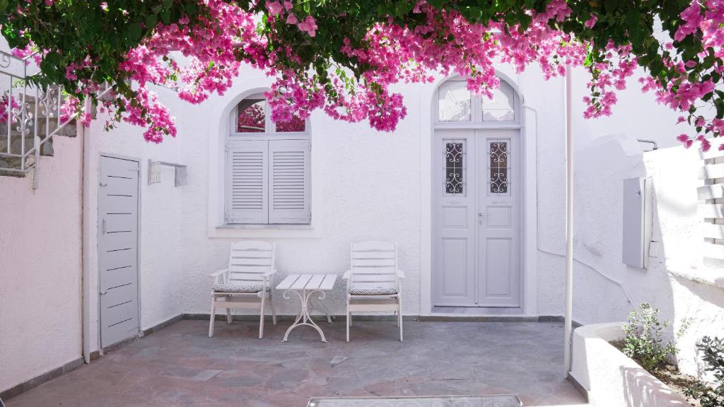 two chairs and a table in front of a white house at White Haven Cave Home in Mesaria