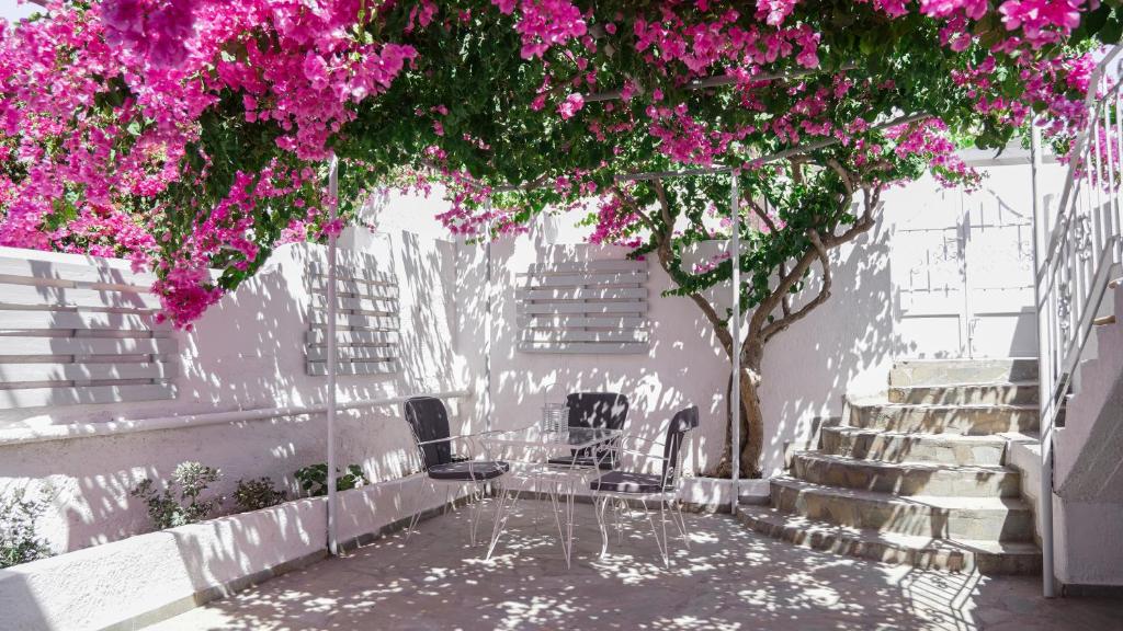 stół i krzesła pod drzewem z różowymi kwiatami w obiekcie White Haven Cave Home w mieście Mesaria
