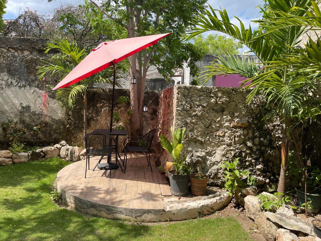 une table et une chaise sous un parapluie rouge dans une cour dans l'établissement Villas Candita, à Mérida