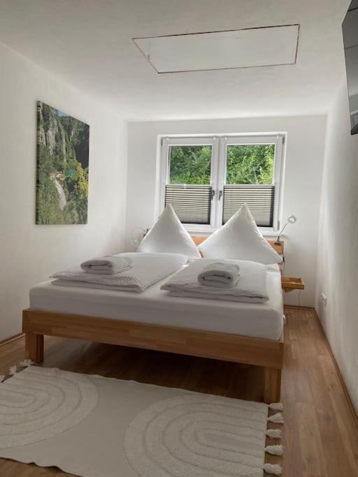 a bedroom with a bed with white sheets and a window at Im Wald in Gleiszellen-Gleishorbach