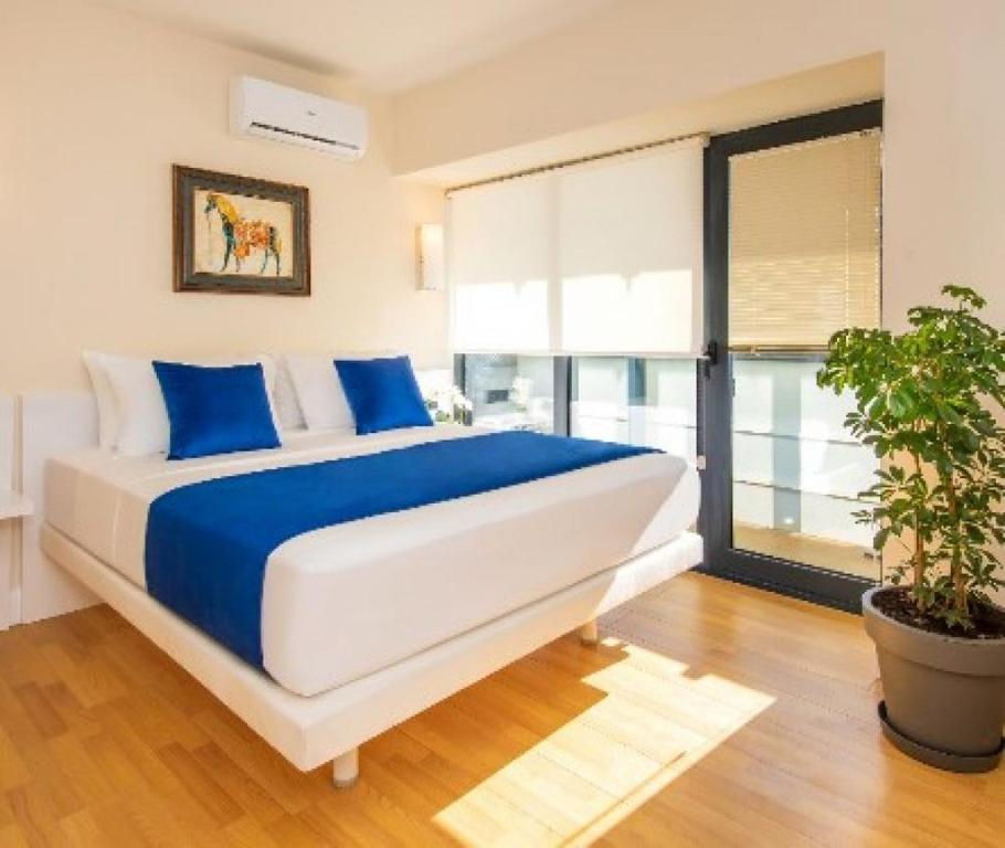 a bedroom with a large bed with blue pillows and a plant at Batumi Orbi City Lux Apartment 5* in Batumi