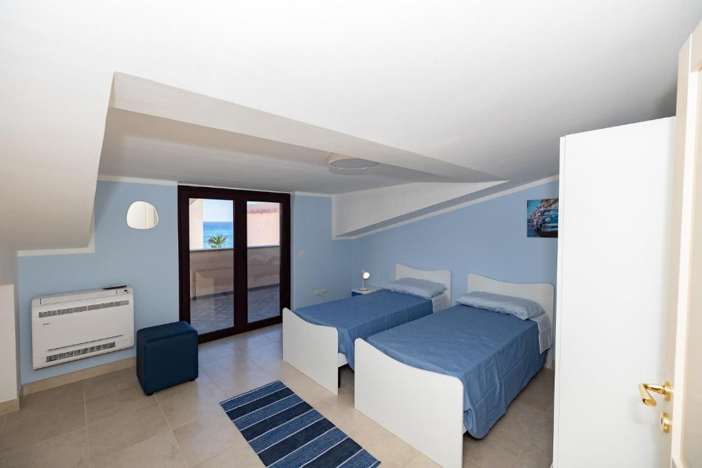 1 dormitorio azul con 2 camas y ventana en Chiaro di Luna Guest House, en Roccella Ionica