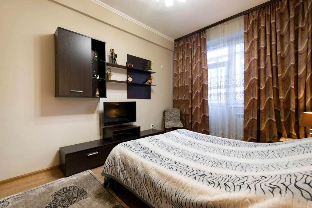 a bedroom with a bed and a large window at Nadezhda Apartments on Kazybek bi st. in Almaty