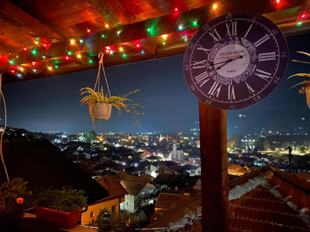 een klok op een paal met een stad in de nacht bij Jelly Apartment in Visoko