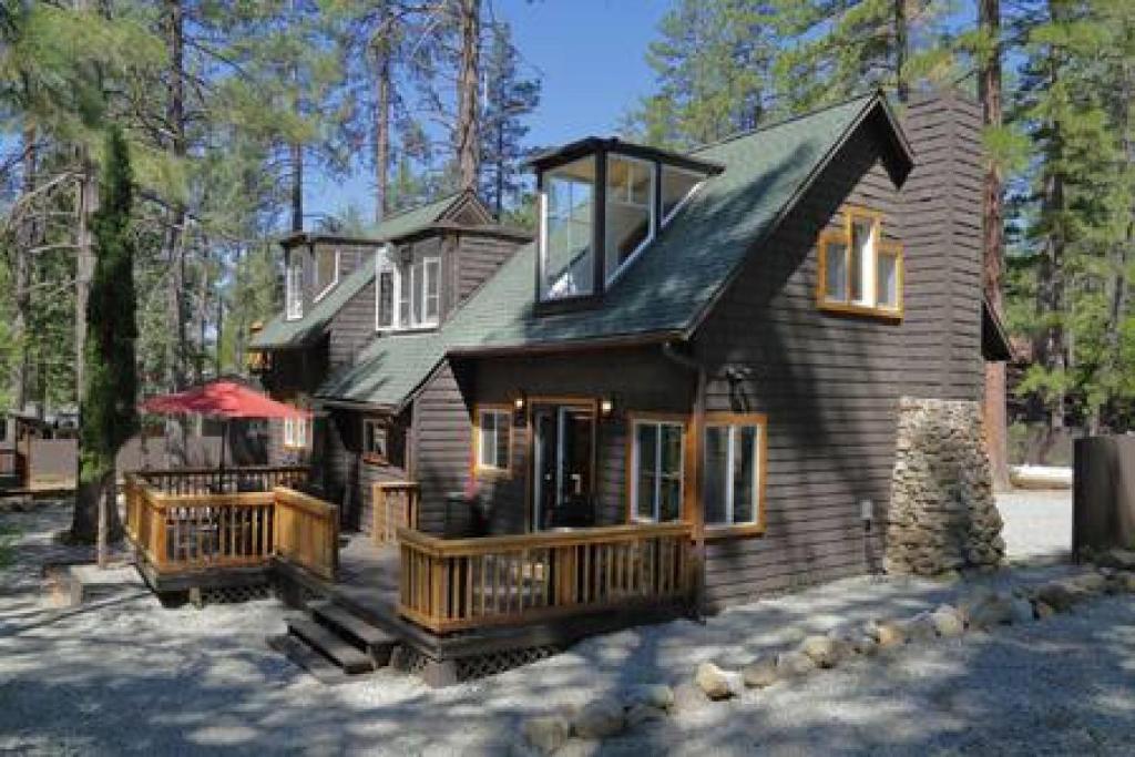 a large wooden house with a porch in the woods at Hobbit House - Charming In Town in Idyllwild