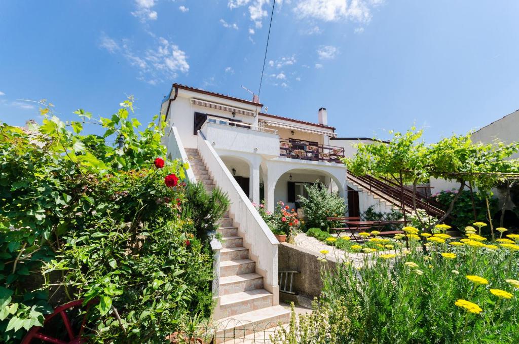 una casa con escaleras en un jardín con flores en Apartments Puntica, en Punat