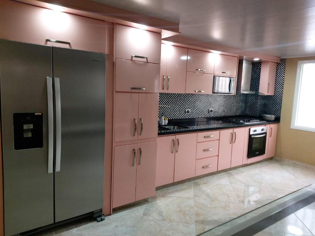 a kitchen with pink cabinets and a stainless steel refrigerator at Lujoso apartamento amoblado a tan solo dos cuadras del parque principal. in Santa Rosa de Cabal
