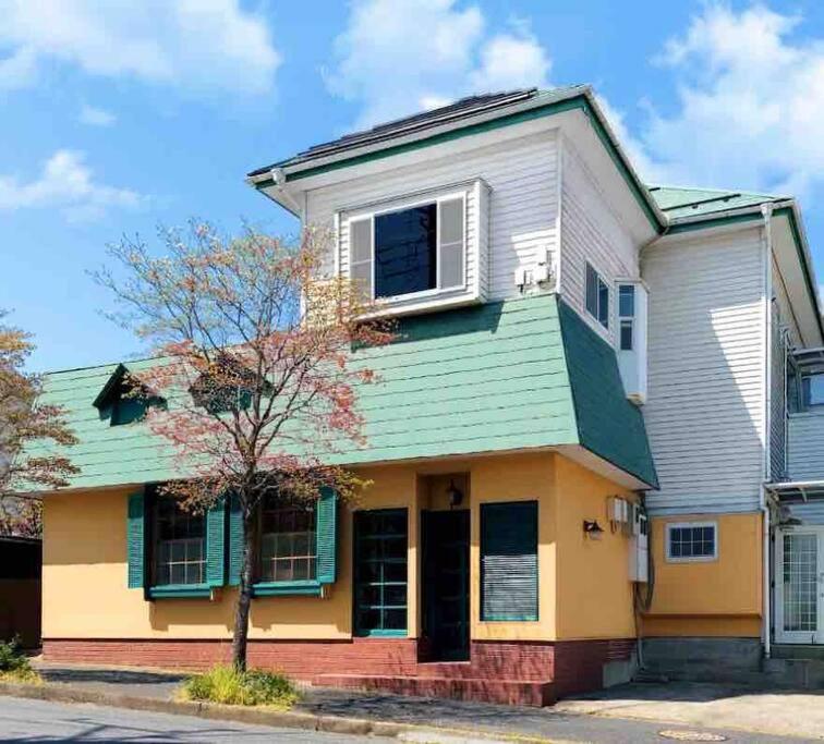 uma casa amarela e branca com um telhado verde em （201室) 成田机场附近宁静惬意的房子，8日以上免费接机 