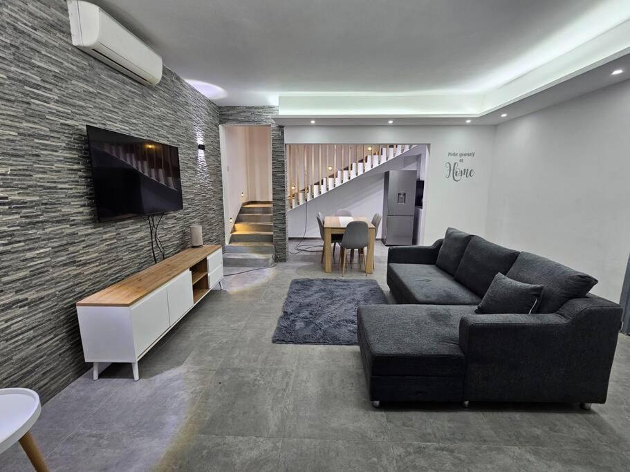 sala de estar con sofá y TV en una pared de ladrillo en Rooftop Spa Luxury Villa, en Rivière Noire
