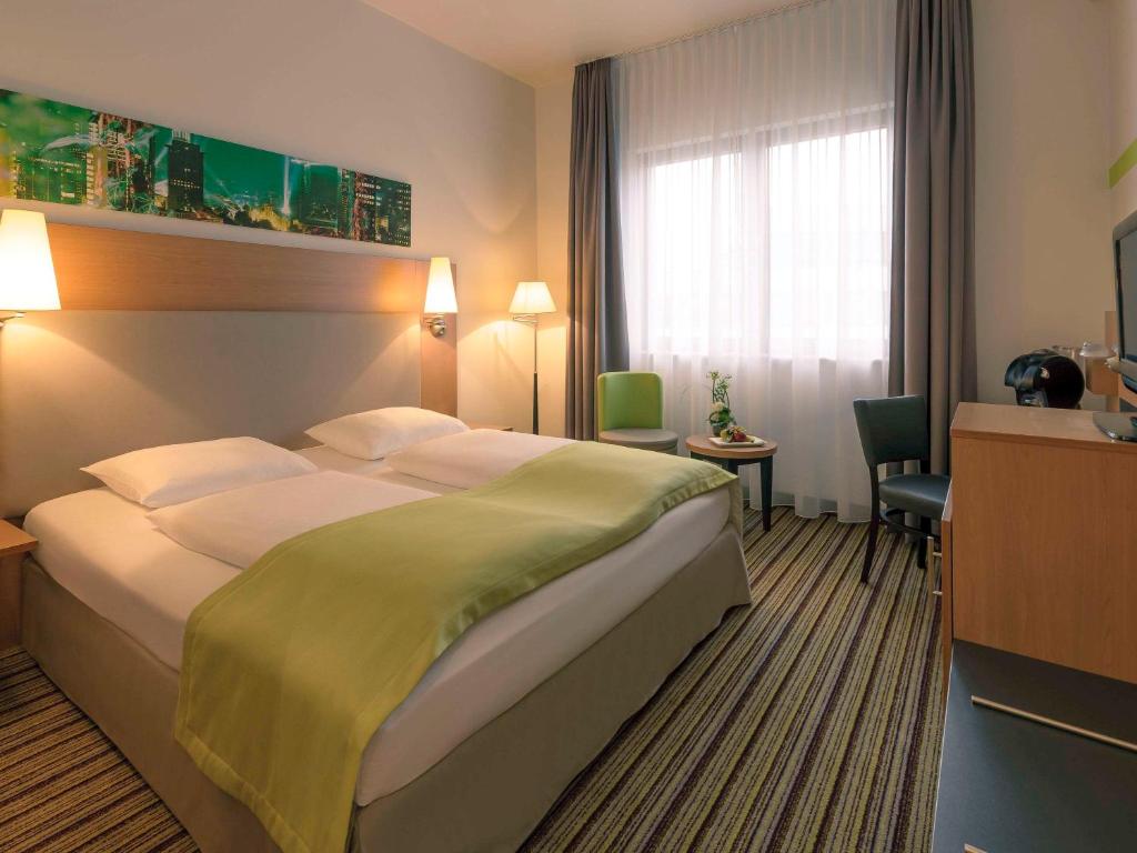 a hotel room with a large bed and a desk at Mercure Hotel Frankfurt Eschborn Süd in Eschborn