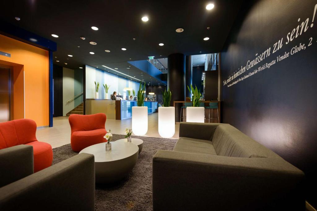 a lobby with a couch and two chairs and a table at Atlantic Hotel Sail City in Bremerhaven