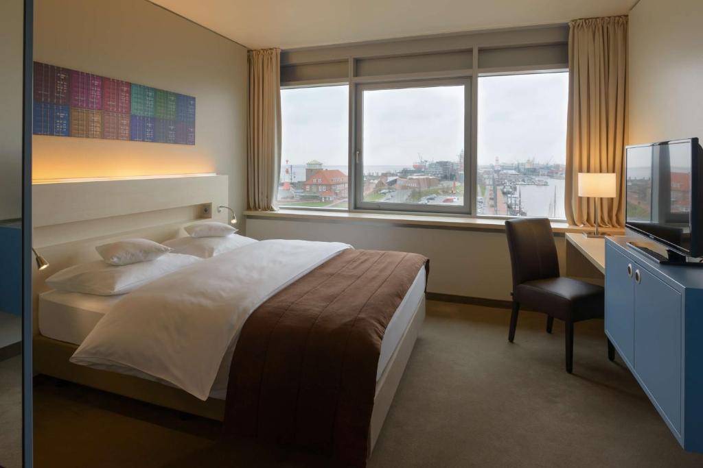 a hotel room with a bed and a desk and window at Atlantic Hotel Sail City in Bremerhaven