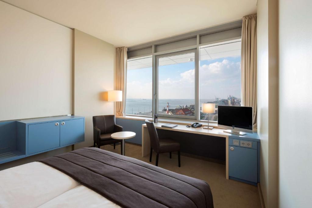 a hotel room with a bed and a desk with a computer at Atlantic Hotel Sail City in Bremerhaven