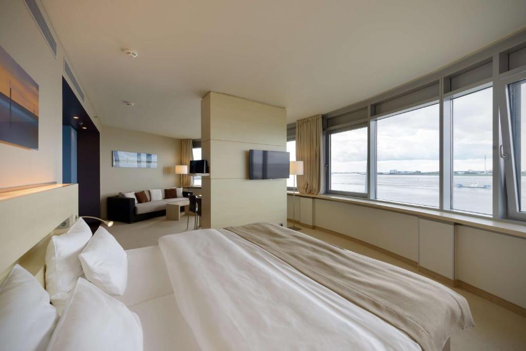 a bedroom with a large bed and a large window at Atlantic Hotel Sail City in Bremerhaven