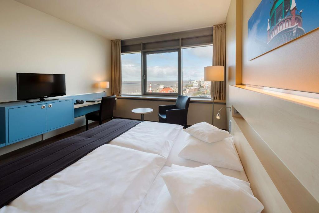 a hotel room with a large bed and a desk at Atlantic Hotel Sail City in Bremerhaven