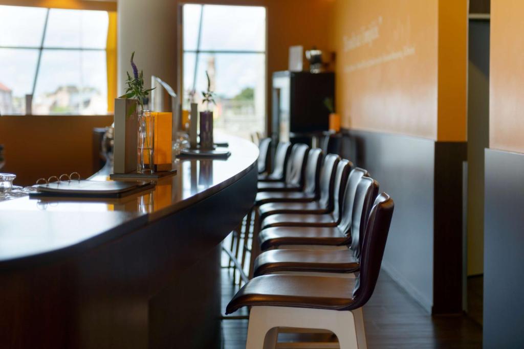 a row of chairs sitting at a bar in a restaurant at Atlantic Hotel Sail City in Bremerhaven