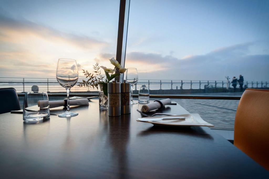 a table with wine glasses and a view of the ocean at Atlantic Hotel Sail City in Bremerhaven