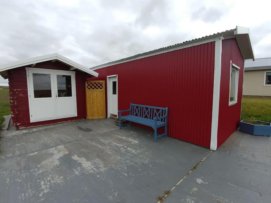 un edificio rojo con un banco delante de él en Stóri-Bakki, cottage Dvergabakki, en Stóri-Bakki