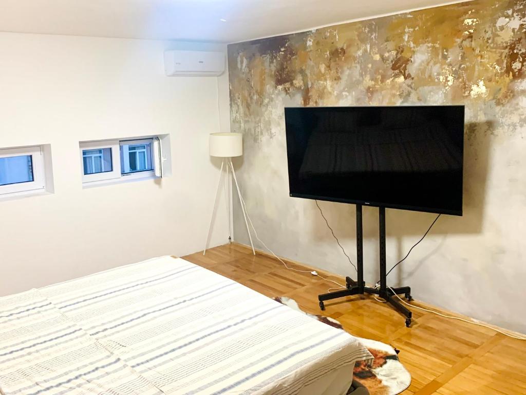 a living room with a flat screen tv and a bed at City Center Square DeLuxe Nest in Podgorica