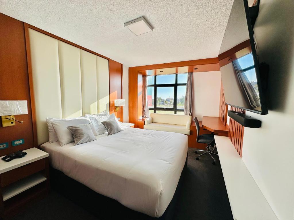 Habitación de hotel con cama grande y escritorio. en OQ MIRADOR CLASSIC - AIRPORT, en Arequipa